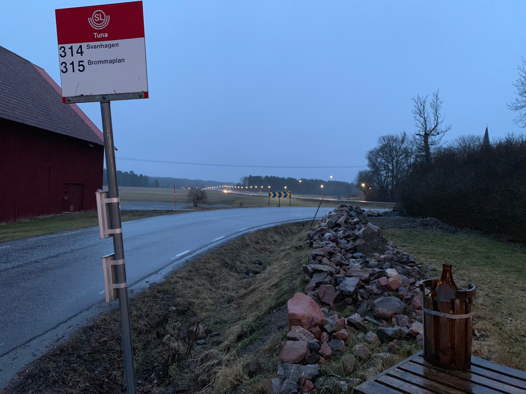 Busshållplats vid landsväg i skymning — vardaglig svensk infrastruktur.