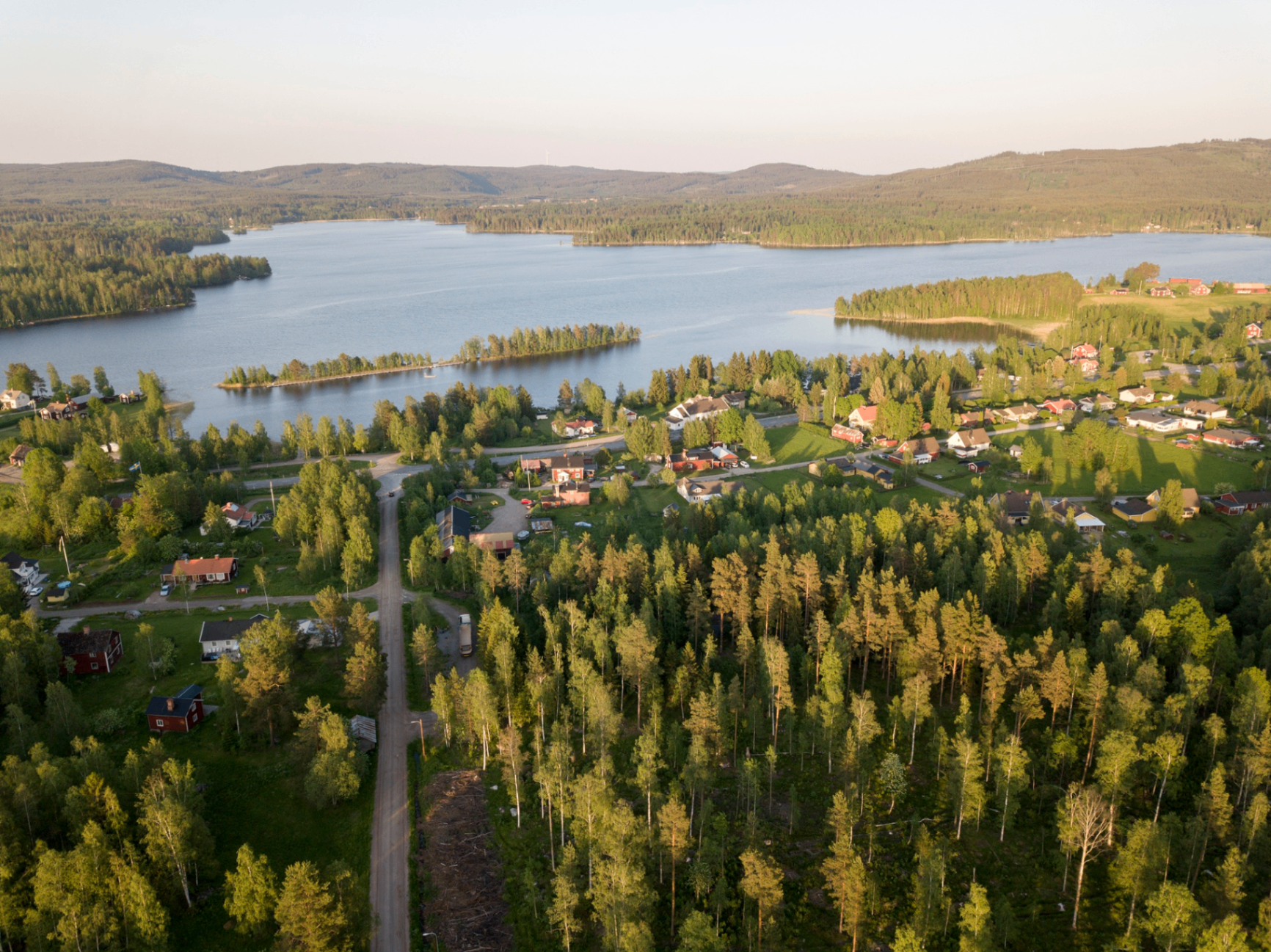 Flygbild över svensk tätort vid sjö, omgiven av skog.